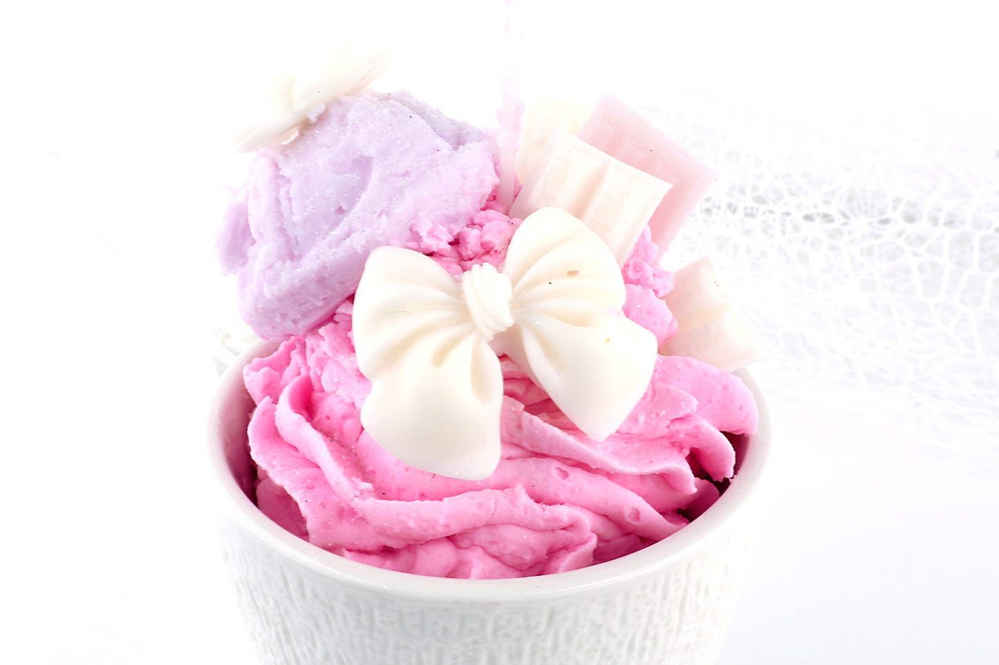 Pastellrosa Dessertkerze im Eiscreme-Look mit Schleifen-Deko, liebevolle Dekoidee für süße Wohnakzente.