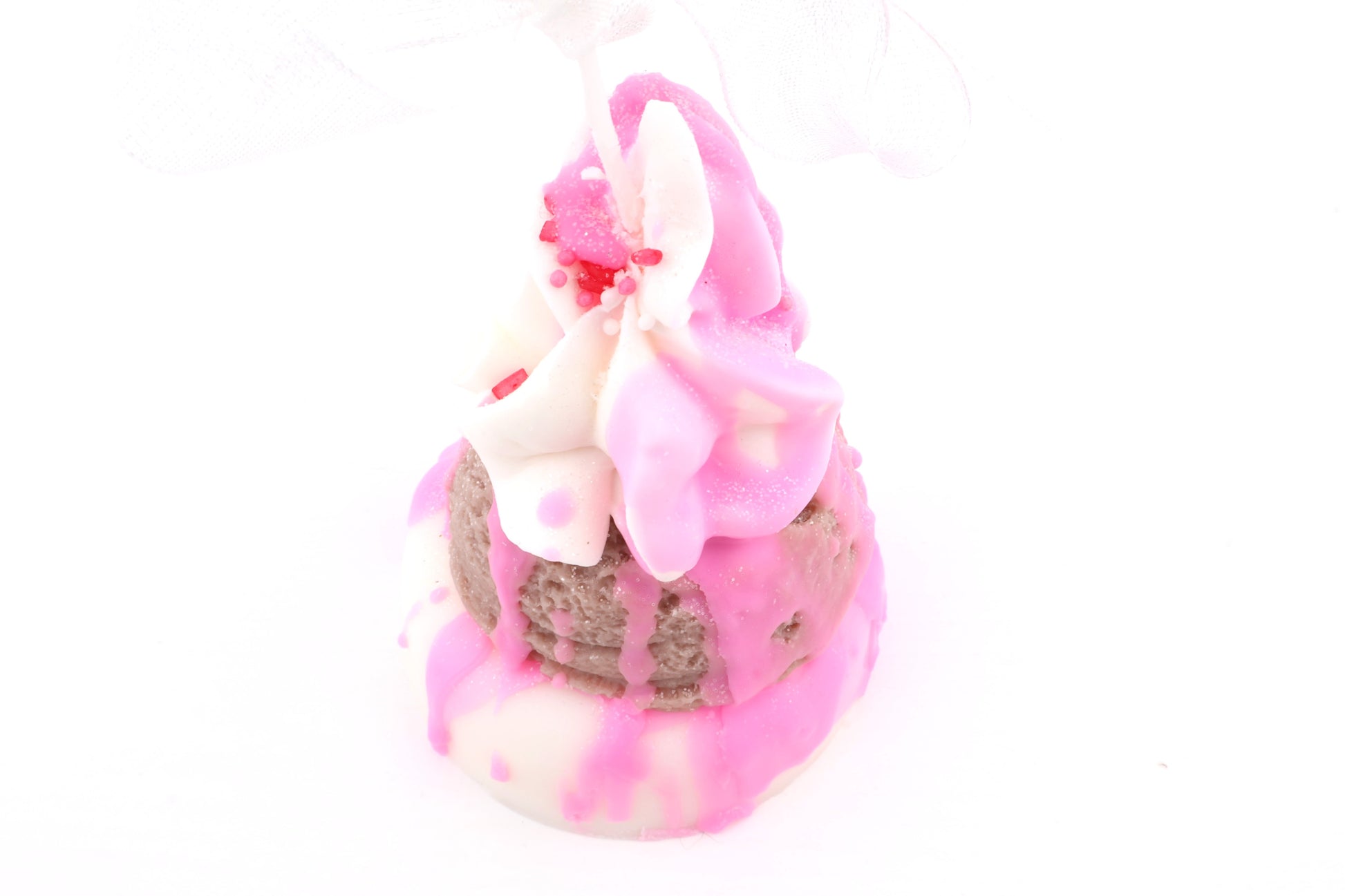 Pink-weiß getoppte Dessertkerze mit rundem Donut-Boden, Mitte braune Eiskugel, Drips, Sahnewirbeln und Sprinkles.