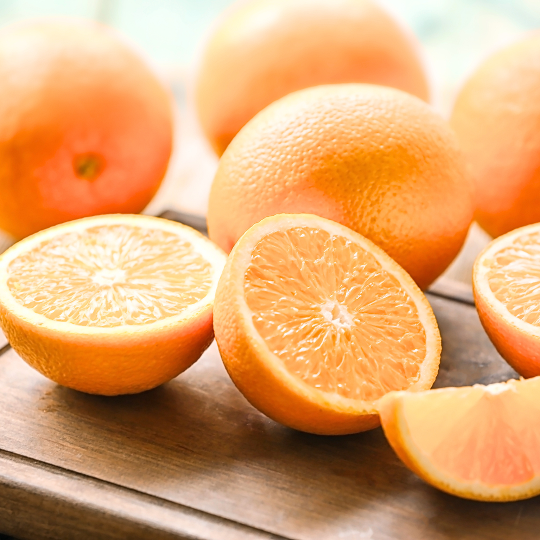 Frische Orangenscheiben und ganze Orangen auf Holzbrett, saftig, leuchtend und natürlich im Warmen licht.