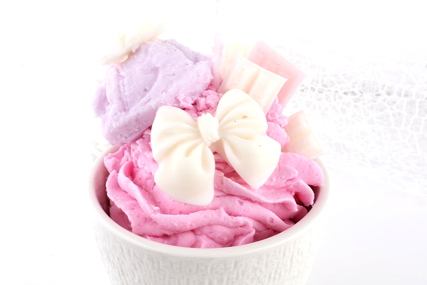 Pastellrosa Dessertkerze im Eiscreme-Look mit Schleifen-Deko, liebevolle Dekoidee für süße Wohnakzente.