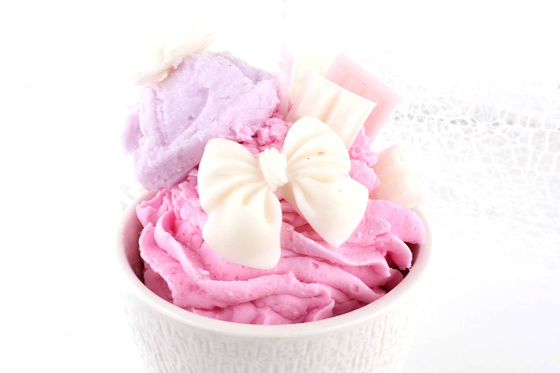 Pastellrosa Dessertkerze im Eiscreme-Look mit Schleifen-Deko, liebevolle Dekoidee für süße Wohnakzente.