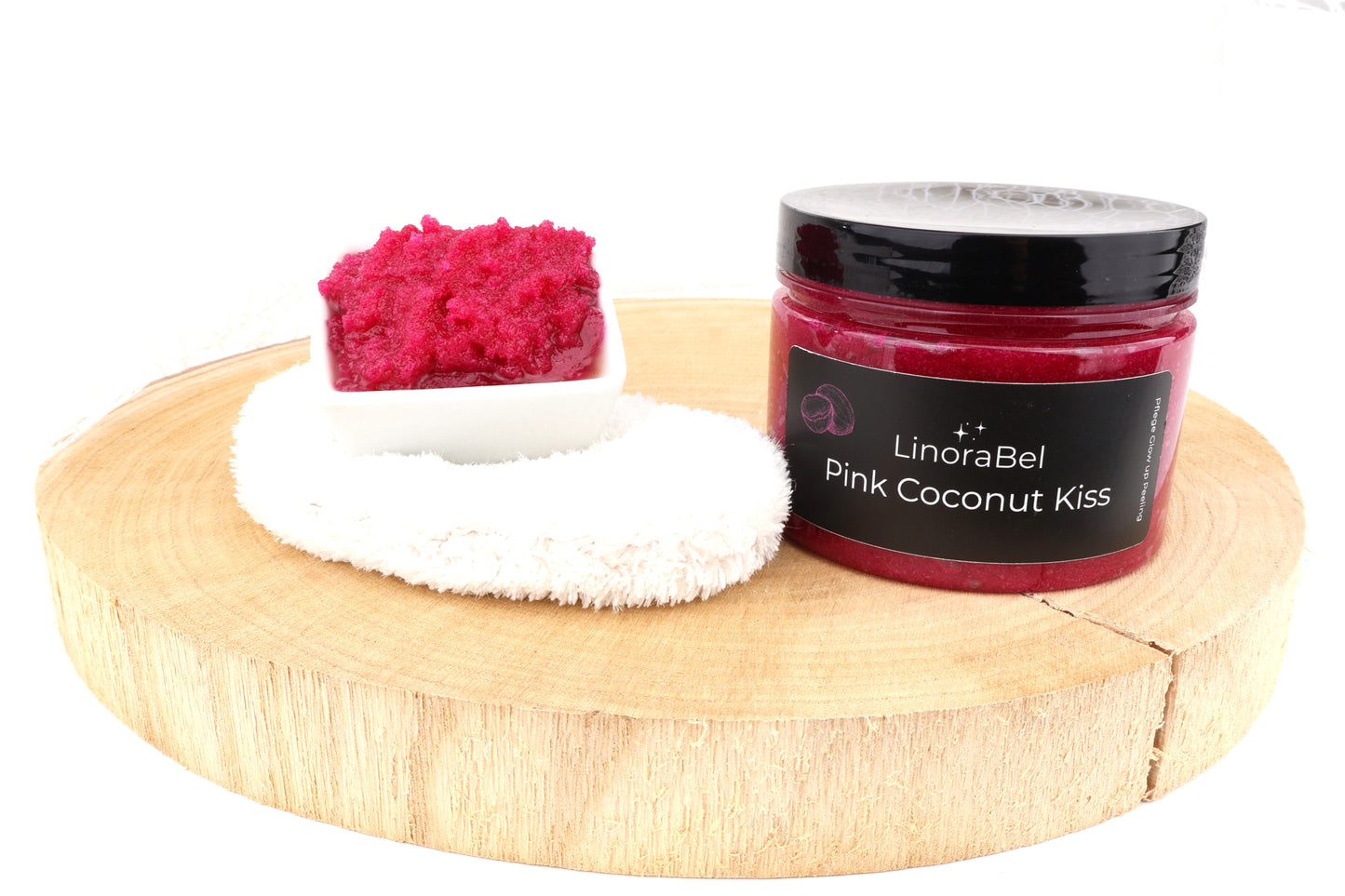 Pink Coconut Kiss Body Peeling im Gefäß, kräftig pinke, körnige Textur, auf Holzscheibe vorgestellt, 100% Bio, vegan.