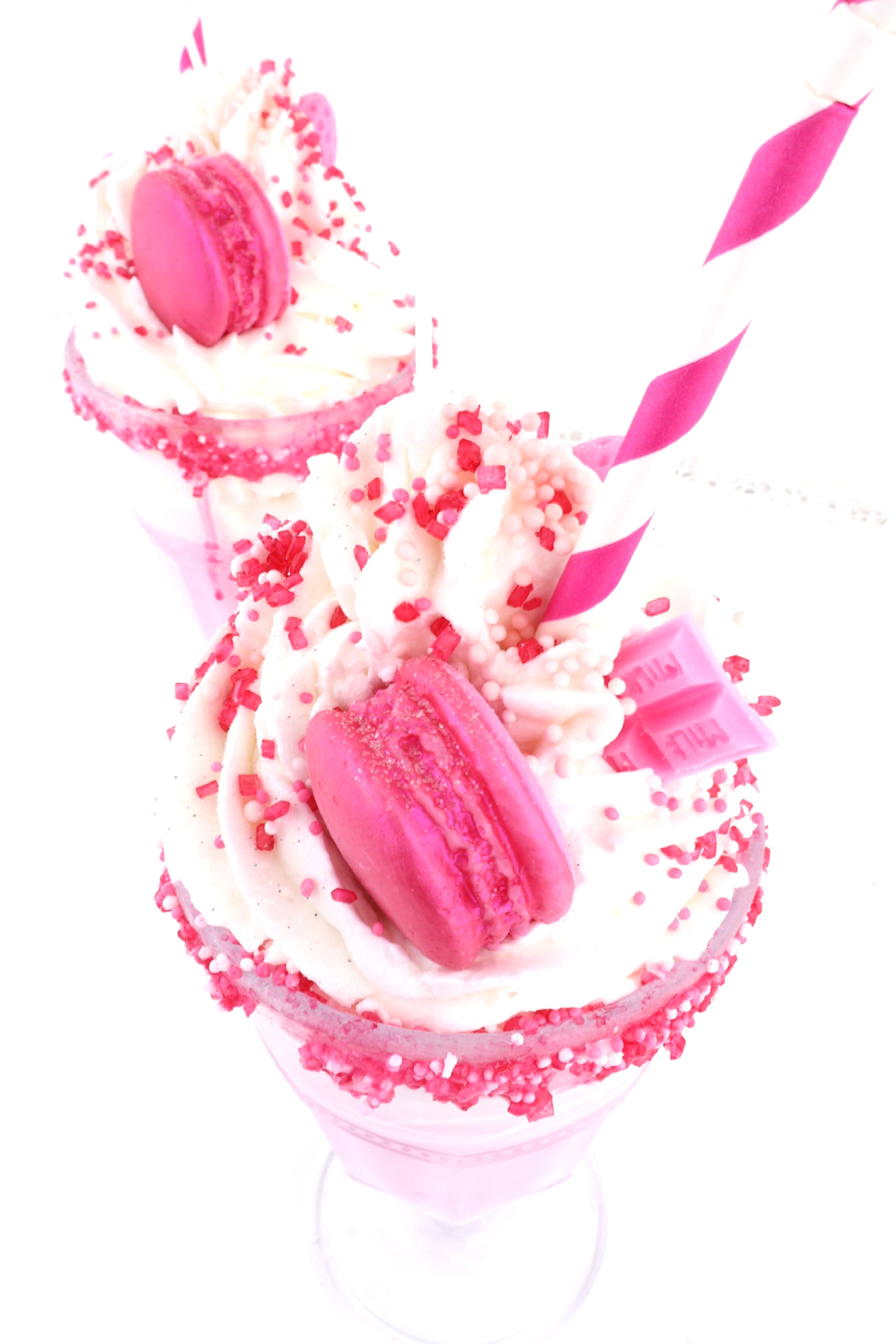 Pinke Dessertkerze im Milkshake-Look mit Sahnetopping, Macaron, Zuckerperlen, Drips und Strohhalm – perfekt als süße Dekoidee