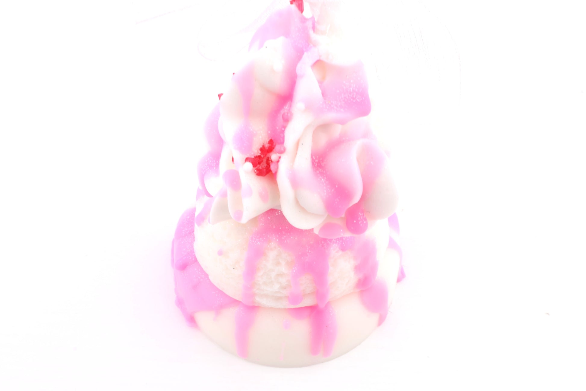 Rosa weißes Dessert mit cremigen Schichten, pinkem Drip-Effekt und dekorativen Details auf hellem Untergrund.